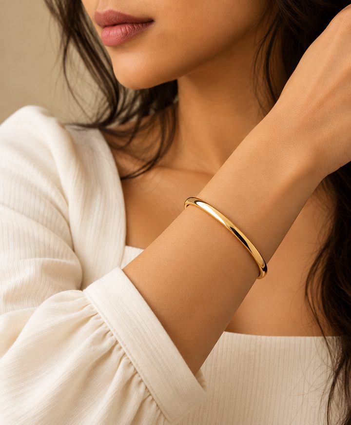 Model wearing a polished gold bangle